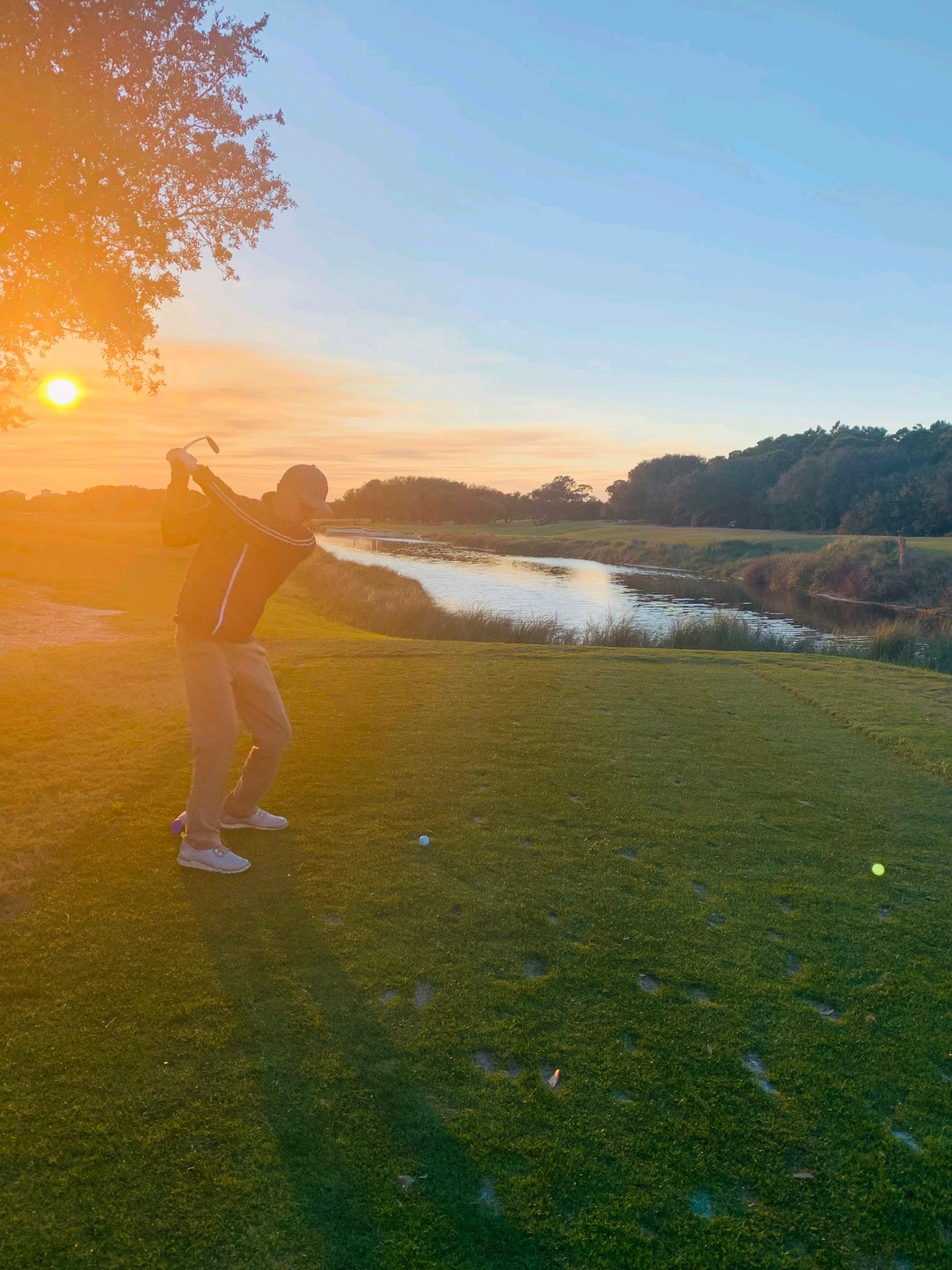 Ryan finishing a sunrise tee shot over water