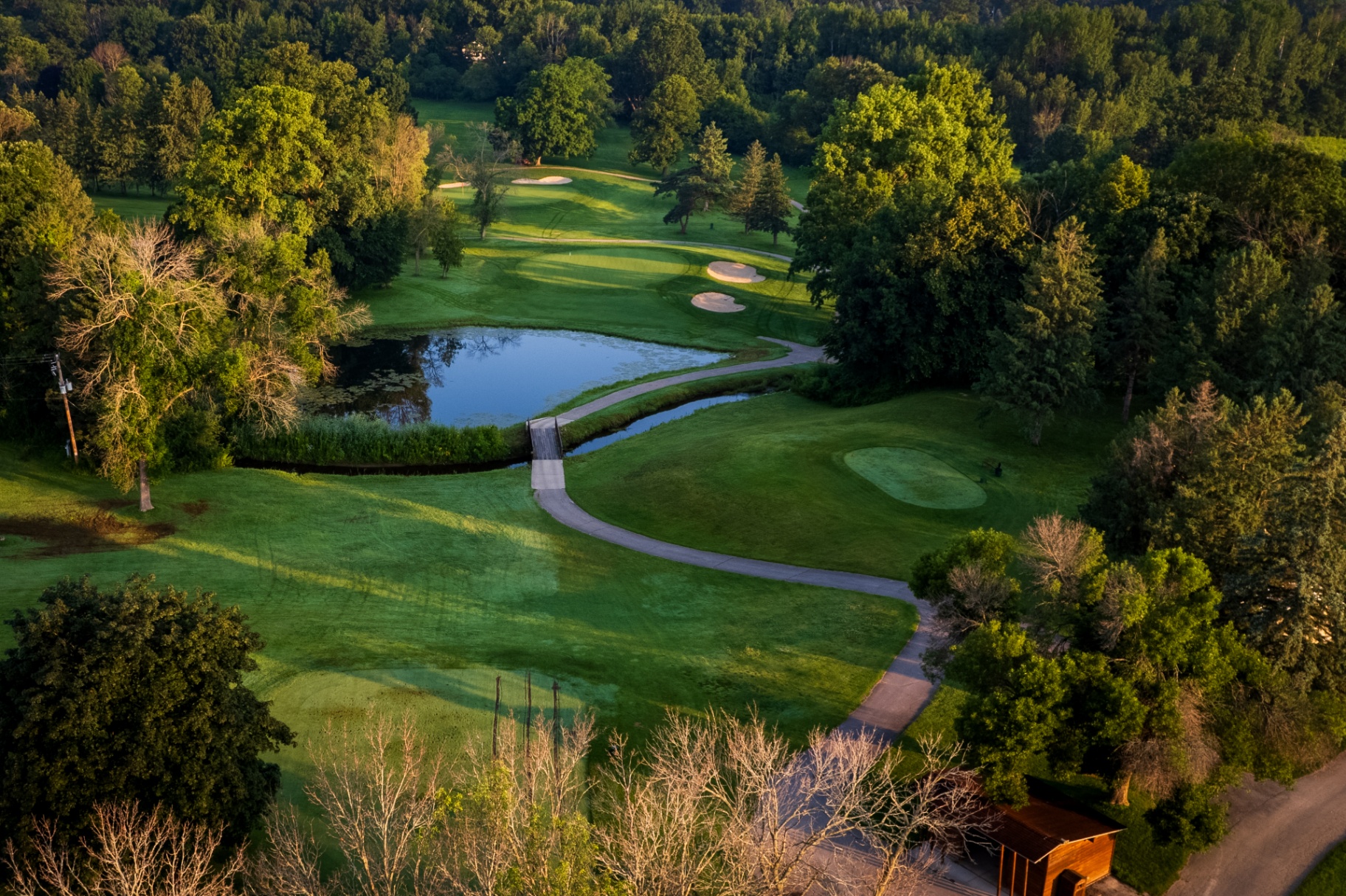 Aerial view of Brown County Golf Course with pond and bridge at golden hour